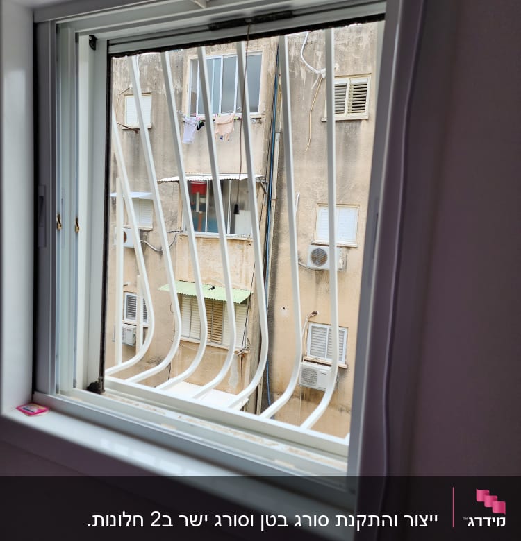 חלון עם סורגים לבנים מול בניין ישן